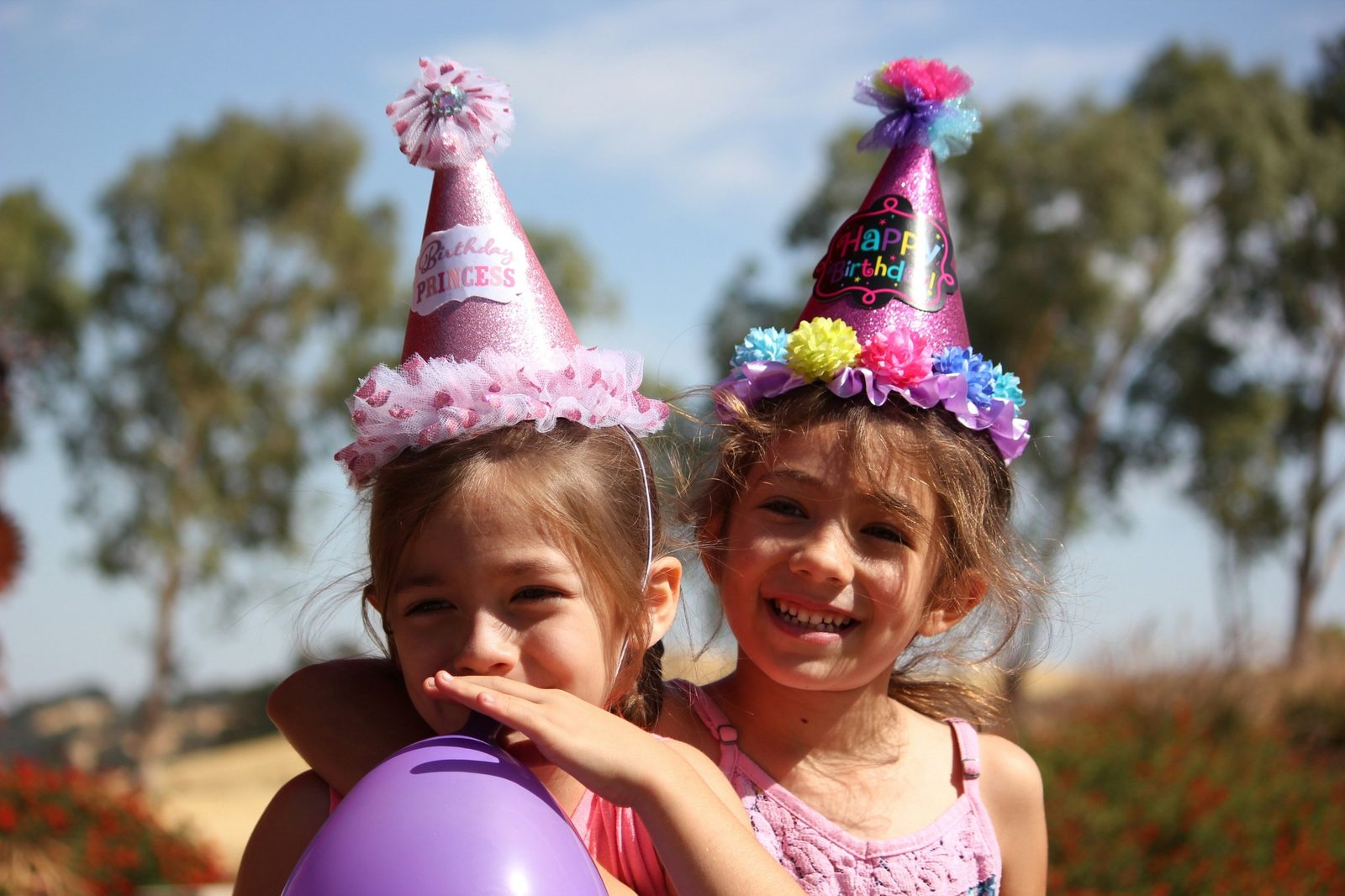 Two little girls in party hats laughing together